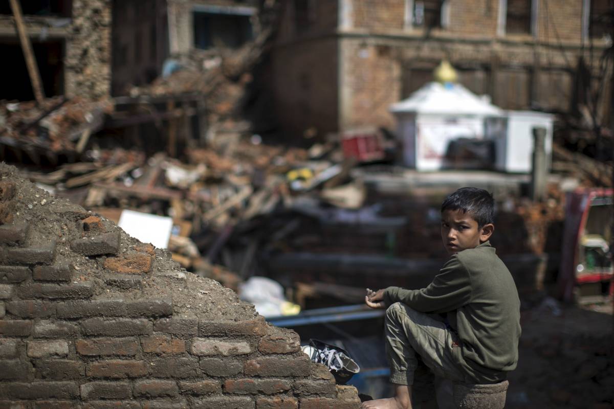 Un ragazzo siede sulle rovine della sua casa a Sankhu, periferia di Kathmandu