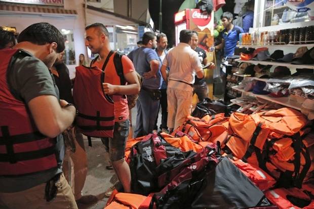 Migranti siriani comprano giubbotti salvagenti in un negozio per turisti a Bodrum