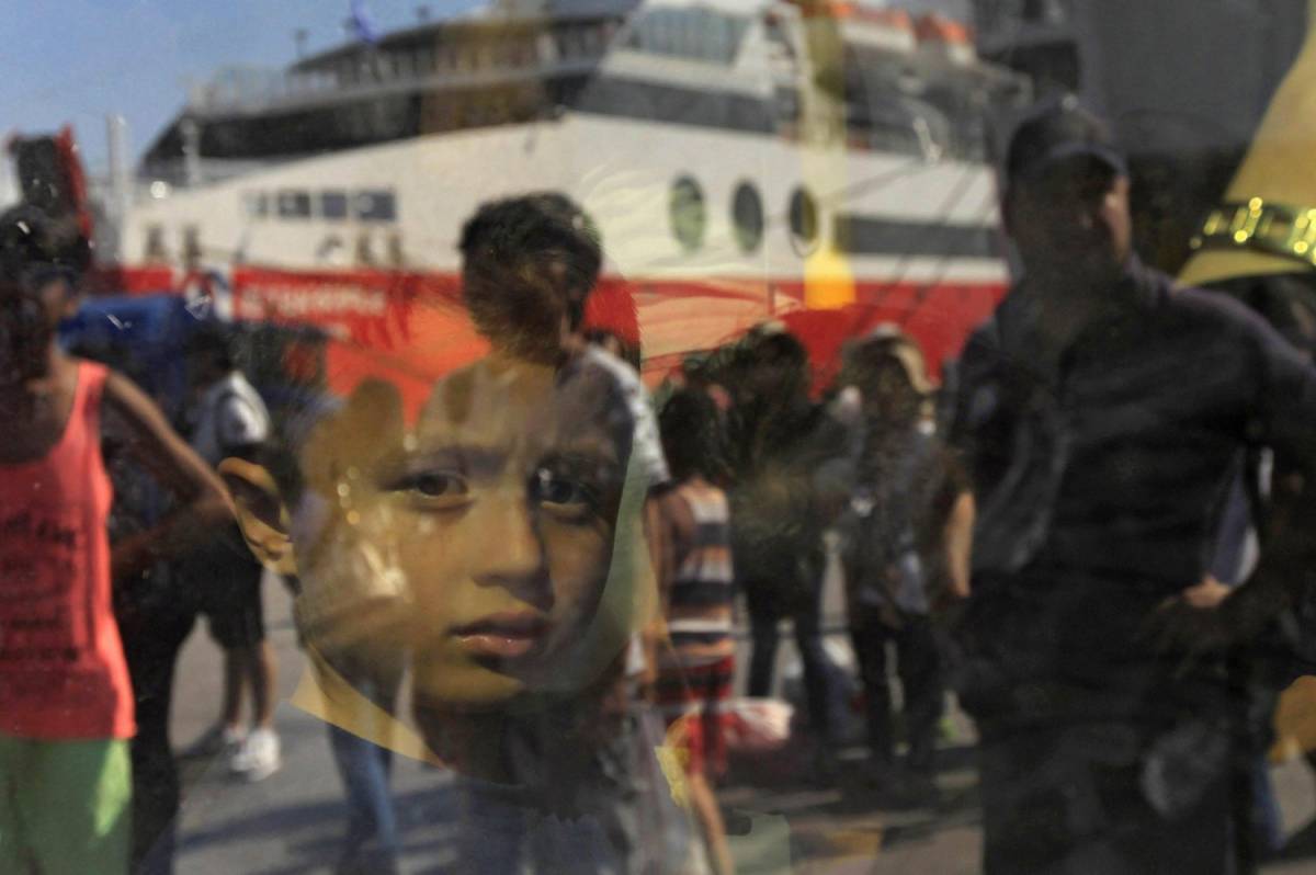 Un bambino siriano alla fermata del bus al porto ateniese del Pireo