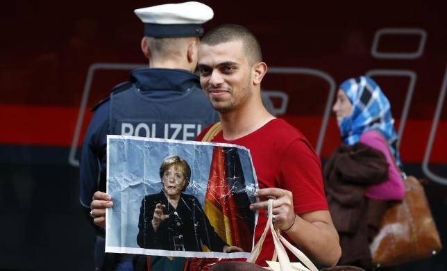 Migranti in viaggio per la Germania esibiscono una foto della Merkel