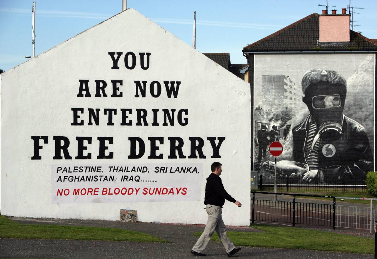 Un uomo passa accanto a un murales che ricorda i fatti del Bloody Sunday