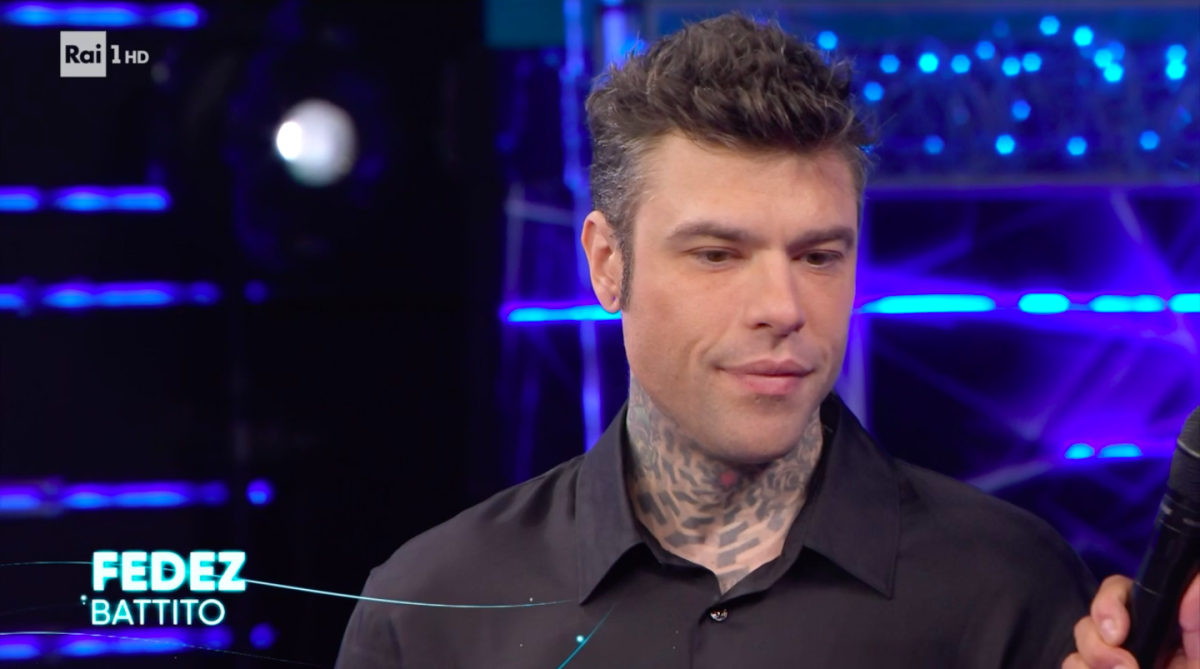 Fedez con l'aria confusa sul palco, Conti lo accompagna nel backstage