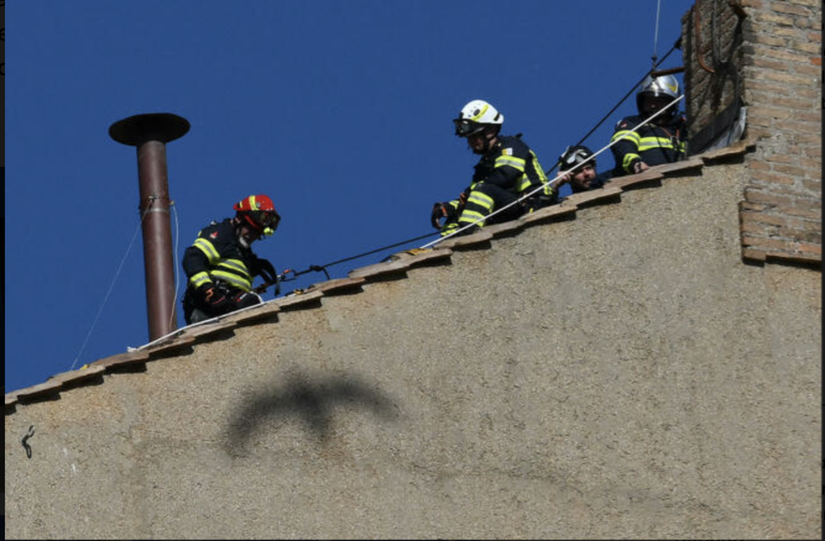 I vigili del fuoco vaticani mentre montano la struttura del camino da cui usciranno le fumate che decreteranno o meno l'elezione del nuovo pontefice